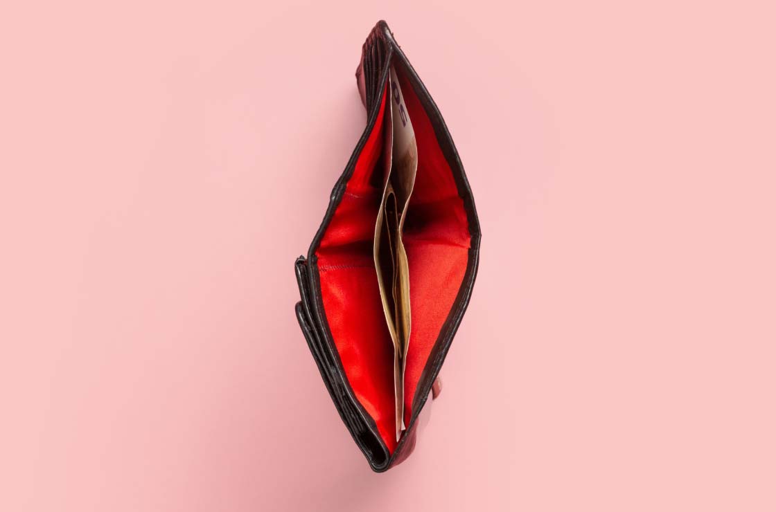 A red wallet with money in it on a pink surface
