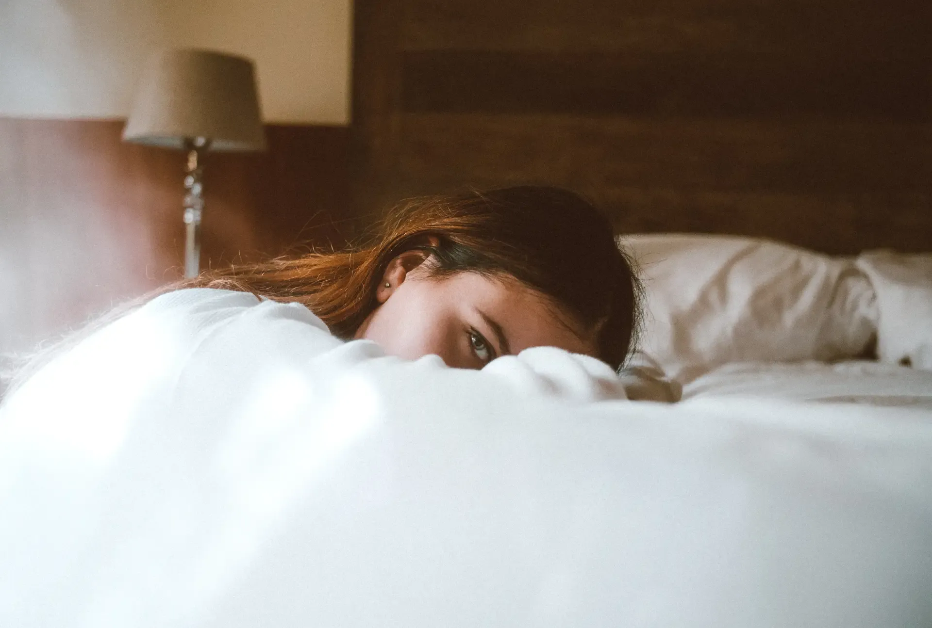 woman kneeling on ground and leaning against bed