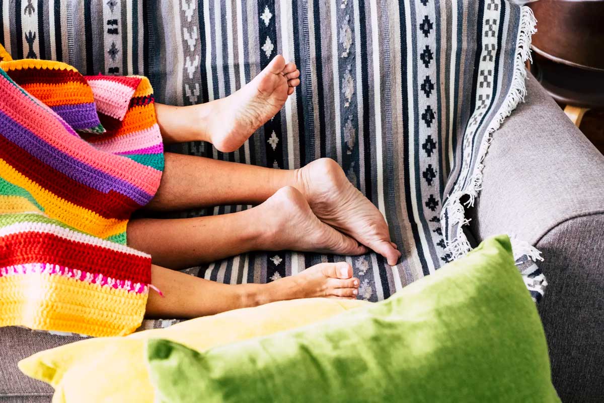 Feet of a couple under a blanket on the couch