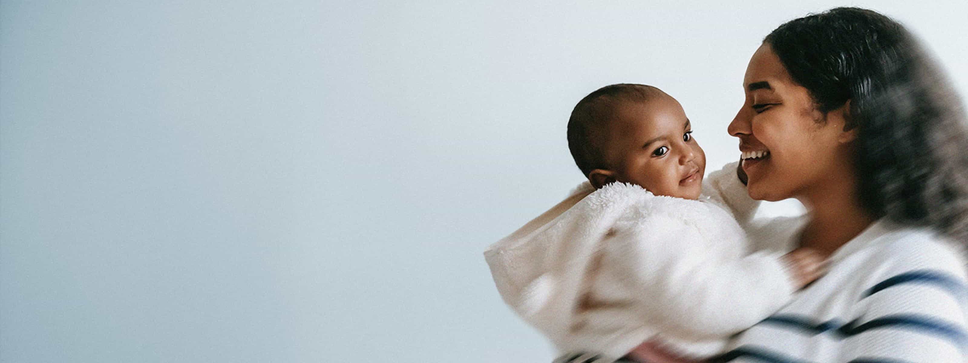 Smiling woman holding a baby, sharing a warm, affectionate moment.