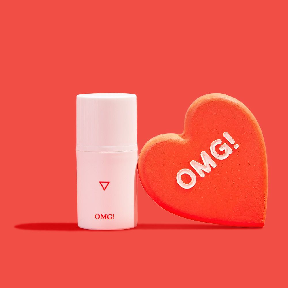 a bottle of Wisp OMG Cream next to a red heart on a red background