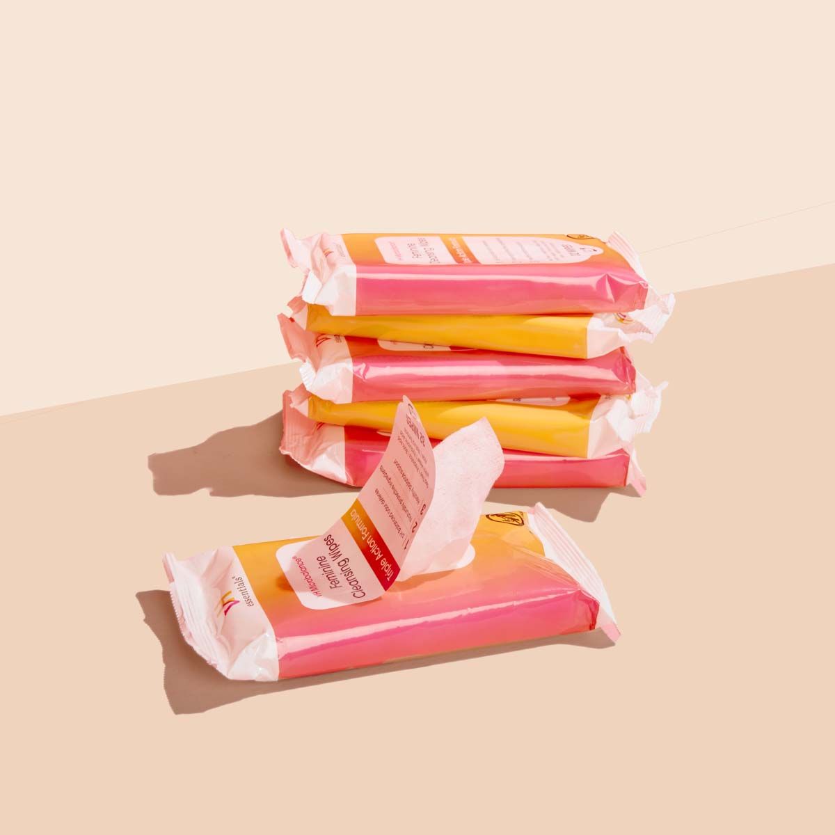 6 packages of pH Balancing Wipes on a cream surface with a red background