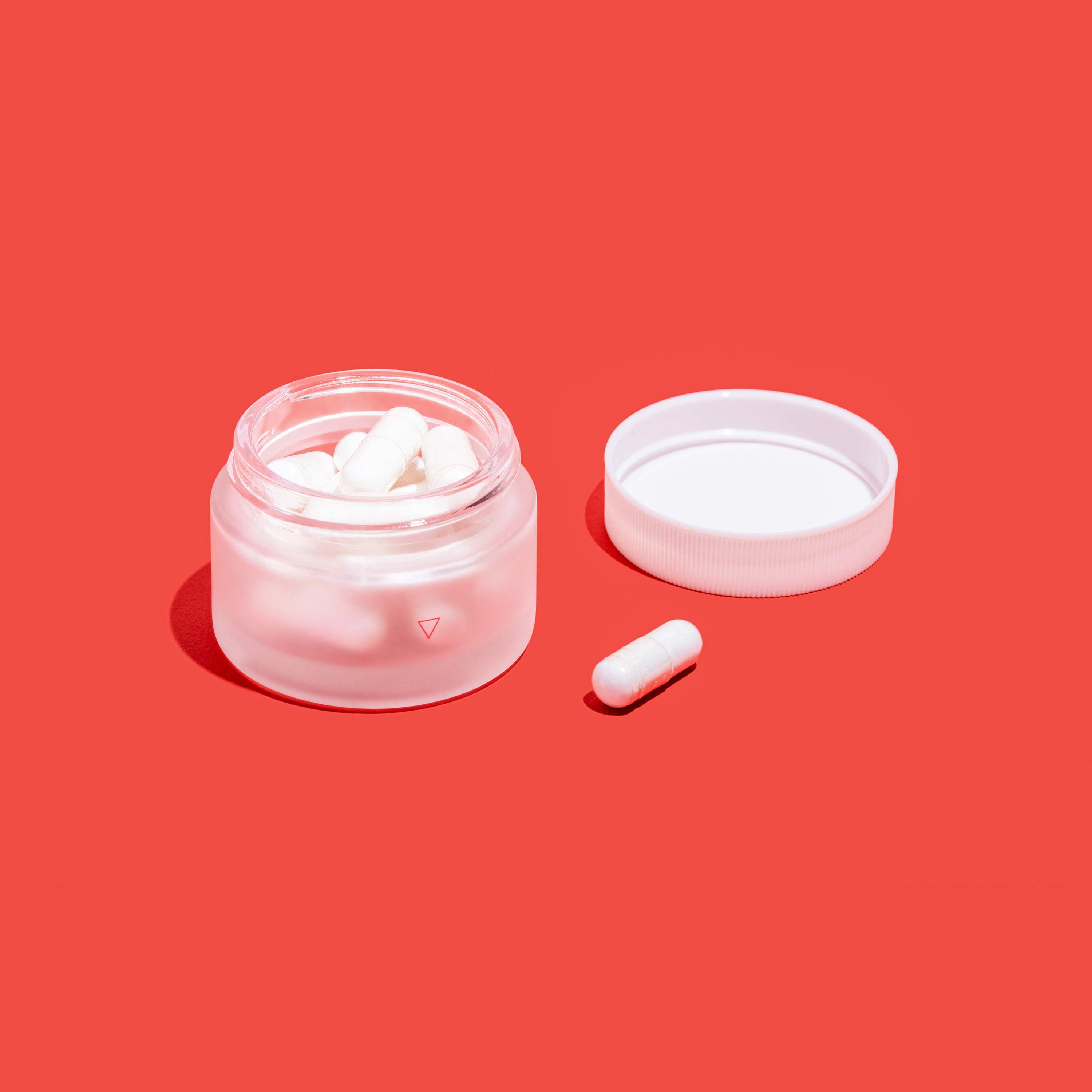 Open jar of boric acid suppositories on red surface