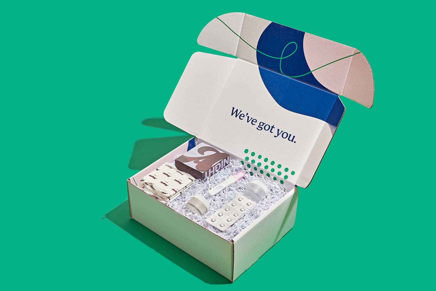 An open Wisp shipping box on a green surface with a medication abortion kit inside