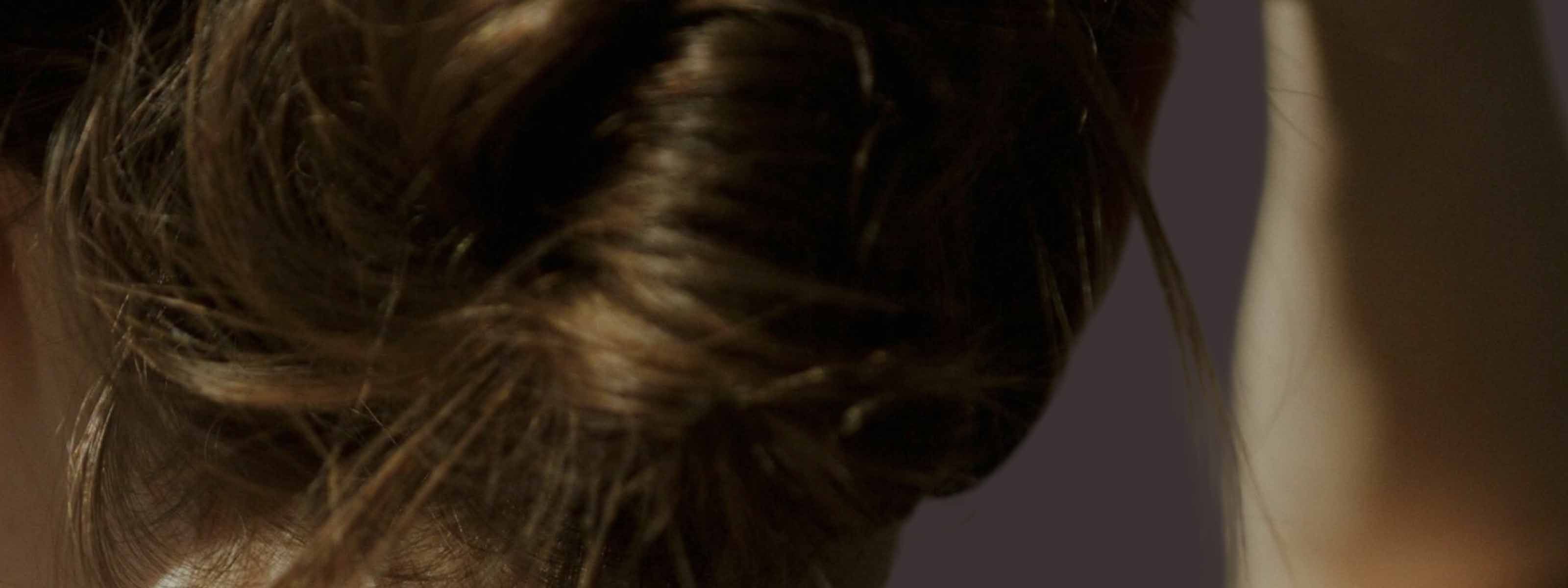 Close up of back of woman's head as she ties her hair up
