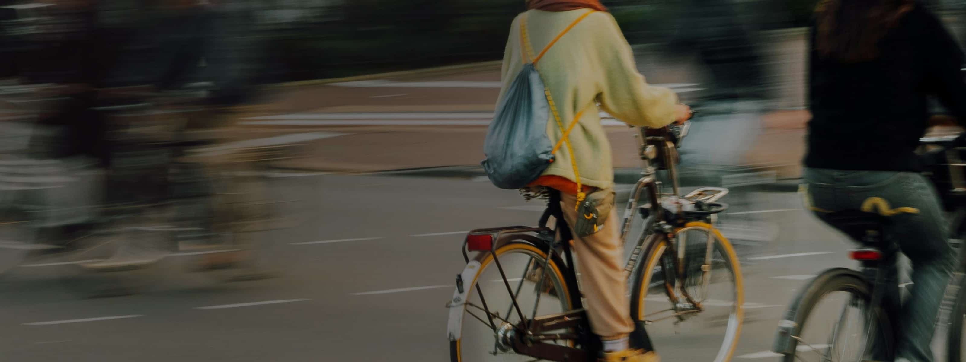 A person riding a bicycle through an urban street, captured with motion blur conveying a sense of speed and movement.