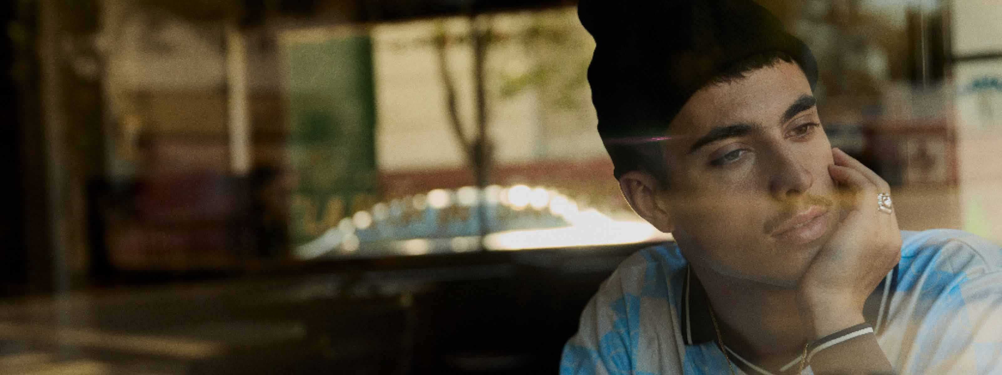 A man resting his chin in his hand while looking out the window with motion blur