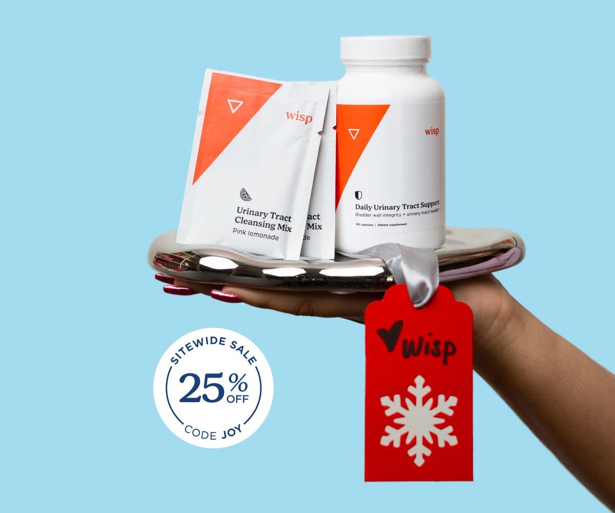 A person's hand holding a silver tray with Wisp UTI medication on it in front of a light blue background