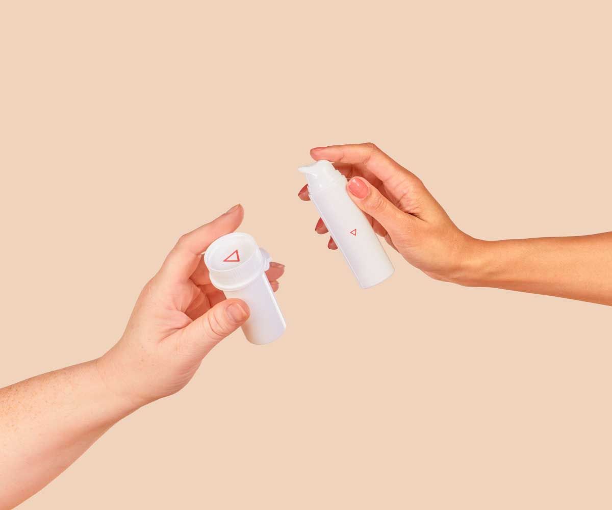 Two people's hands holding a Wisp pill vial and a Wisp pump bottle with a cream background