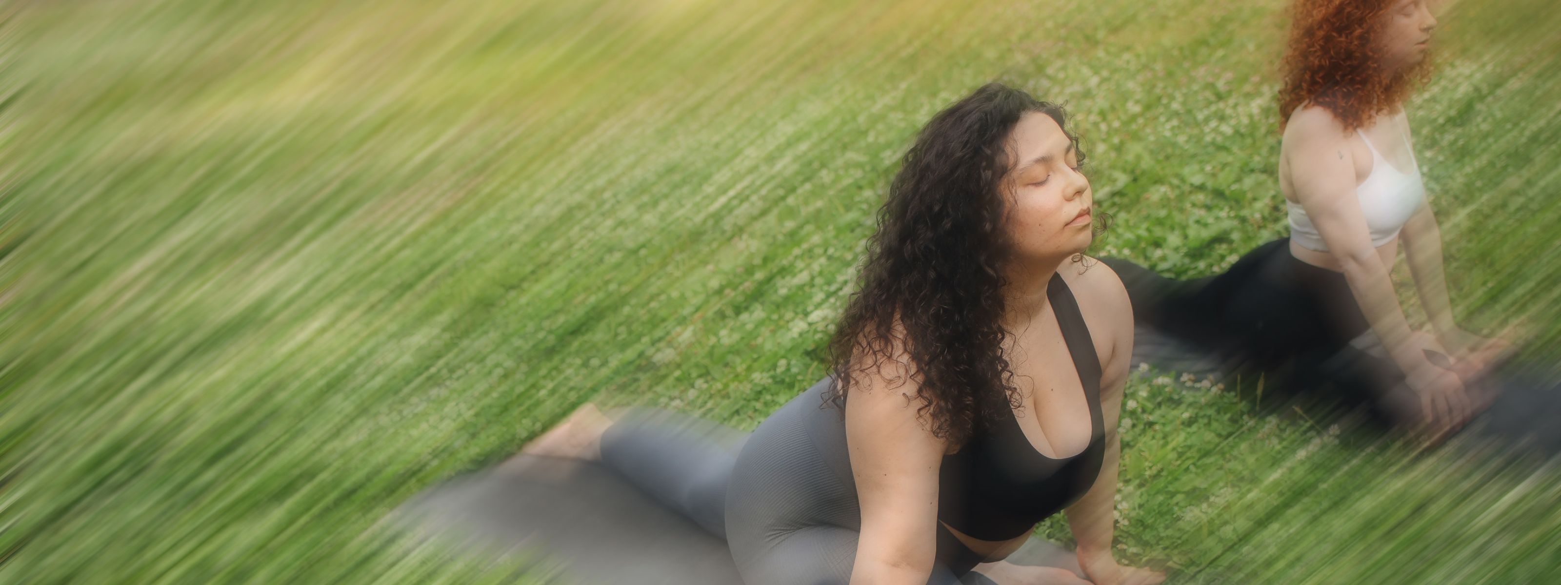 slightly blurry image of two women stretching in a grass field
