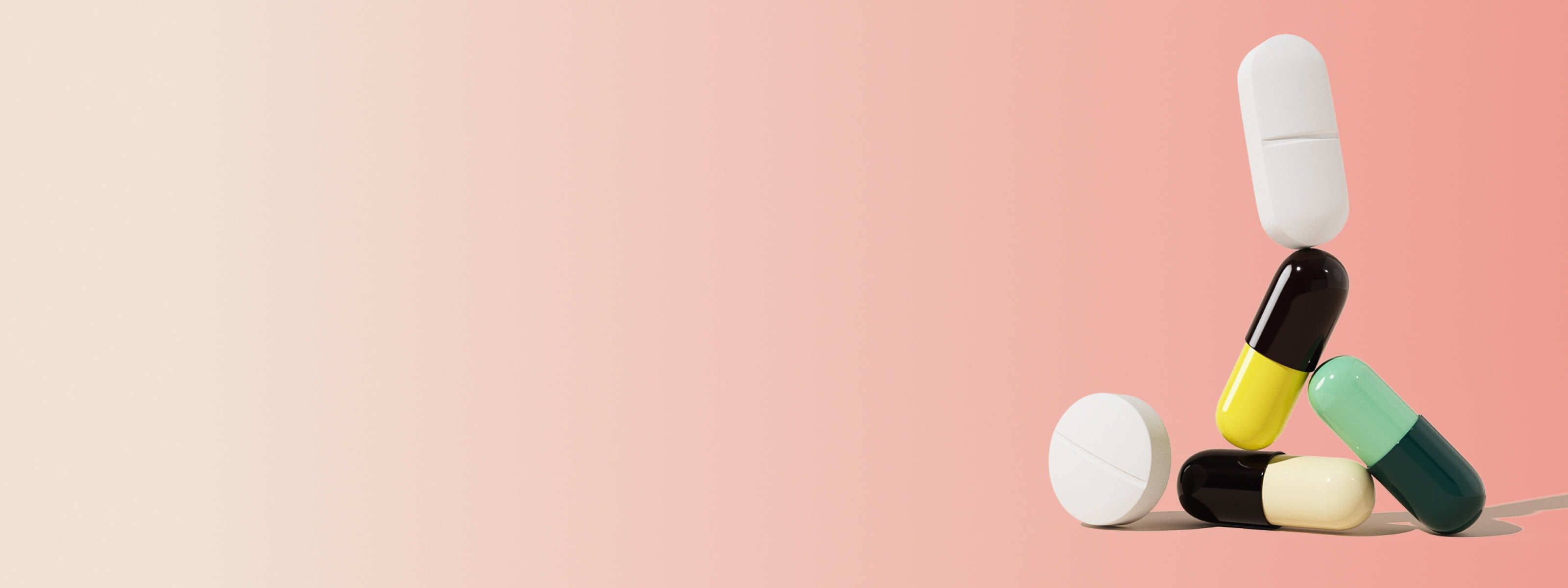 various uti medication pills in front of a gradient pink and beige background