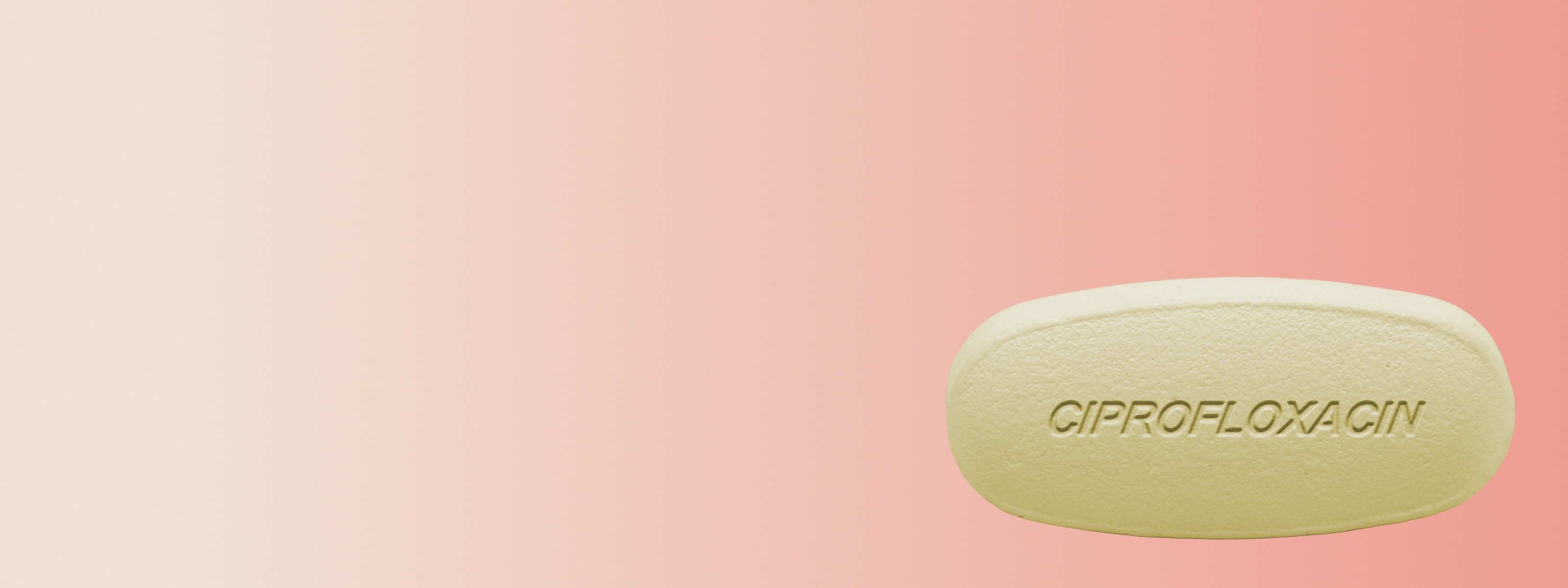Ciprofloxacin pill in front of a light orange and beige background