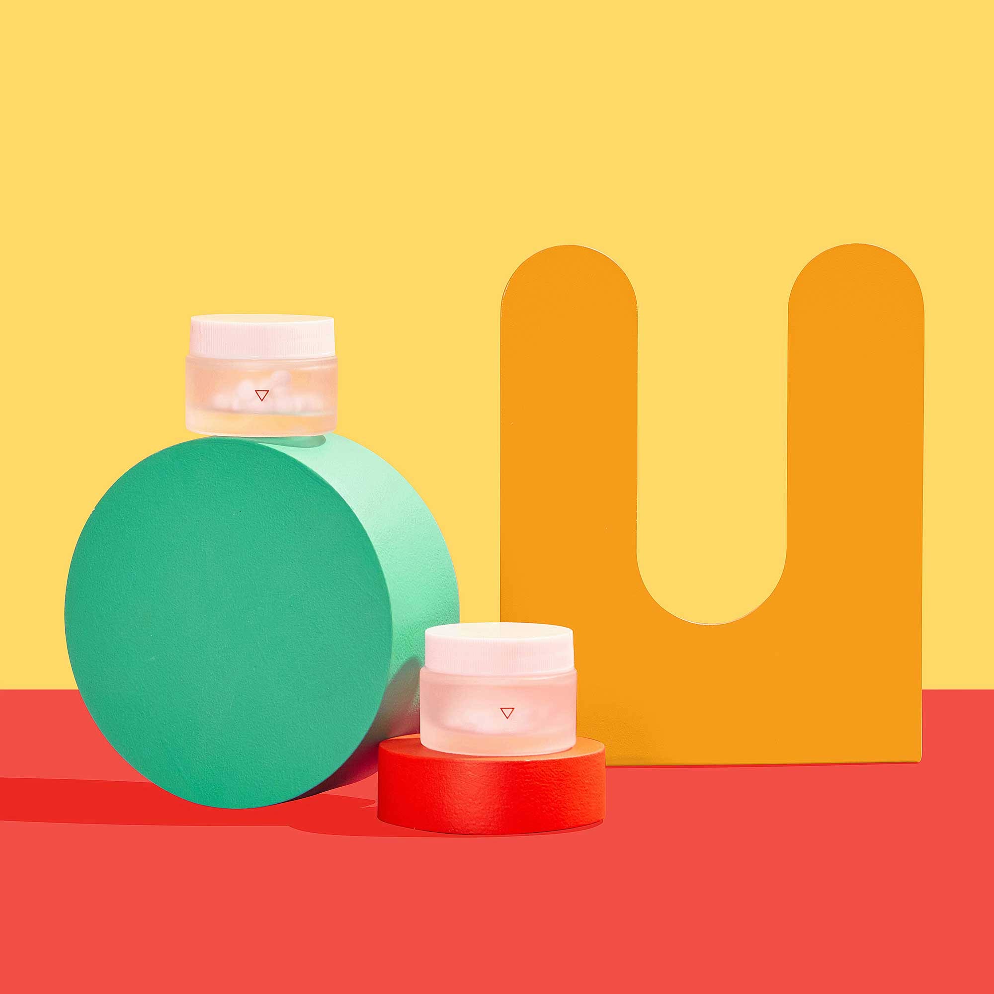 Pill bottles on red and yellow background with colorful geometric shapes