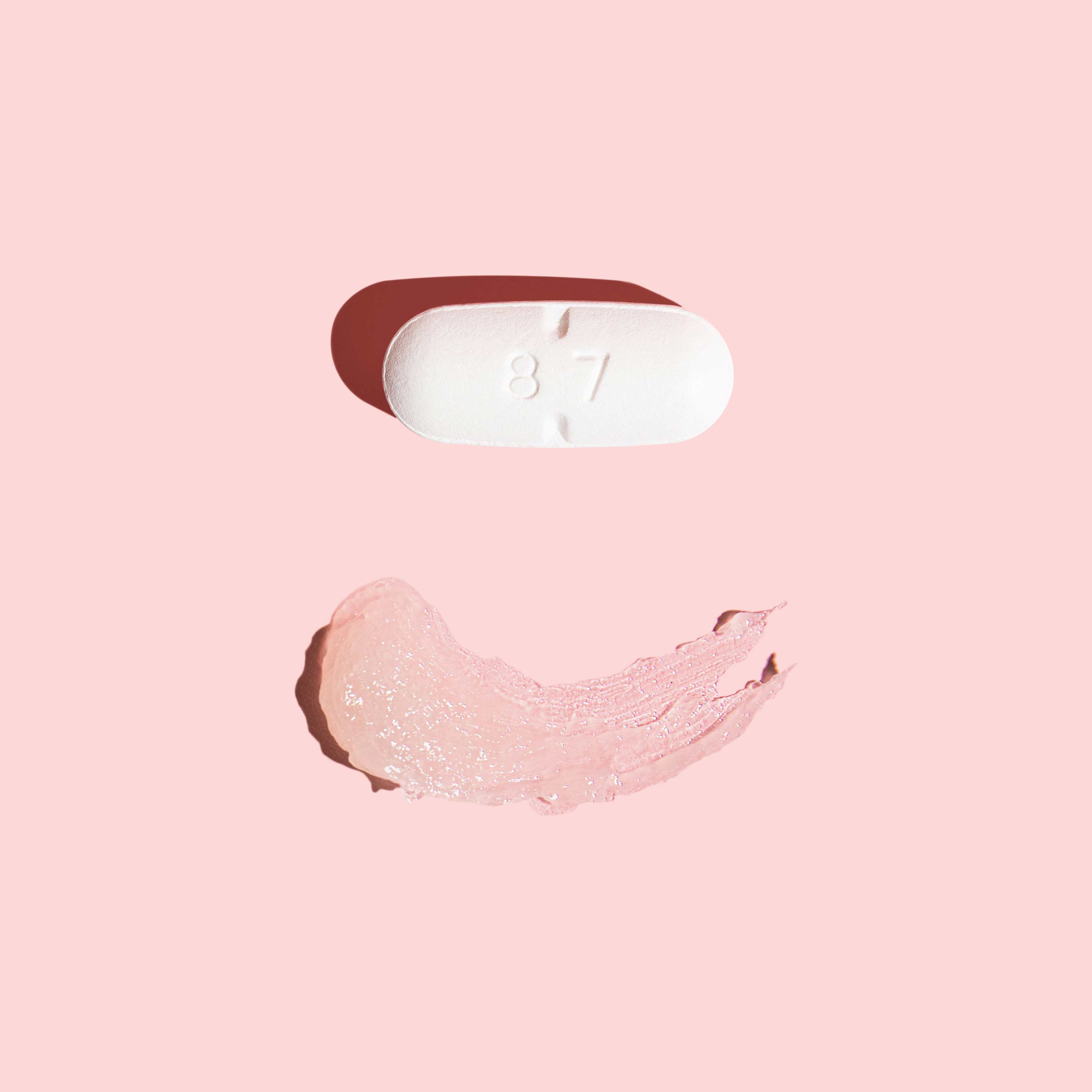 Oral acyclovir pill and smear of topical acyclovir cream on pink background