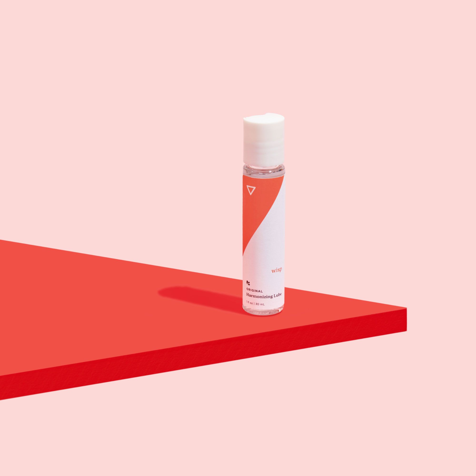 Wisp Harmonizing Lube on a red surface on a pink background