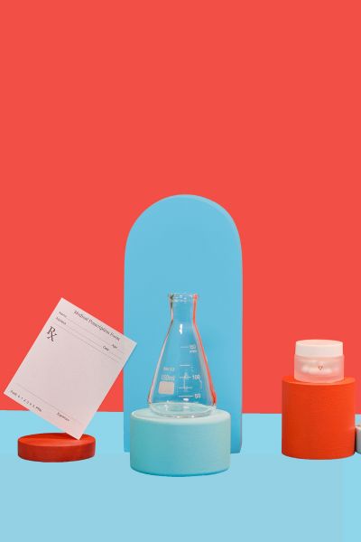 Man's hand reaches for phone sitting next to lab slip, reproductive health medications, and test tubes on colorful geometric background