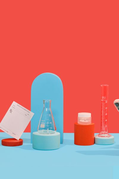 Woman's hand holding phone with wisp pill bottles, test tubes and rx form on red and blue background