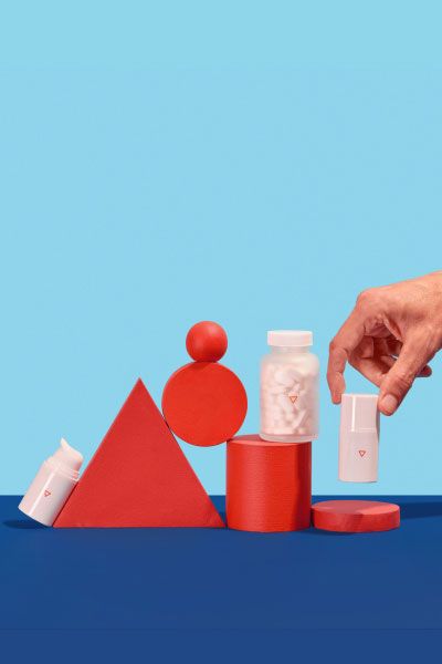 A man's hand picking up herpes medication from a colorful geometric background