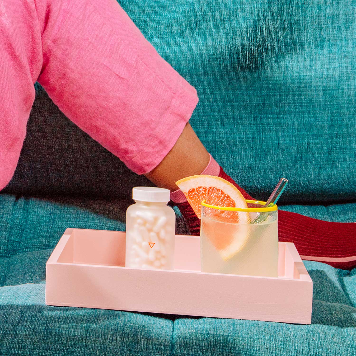 All-Natural Herpes Treatment on a pink tray with a refreshing drink on a green sofa