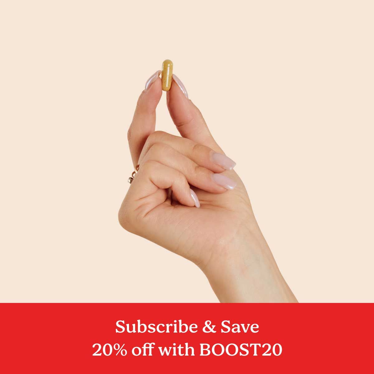 A hand holding a Wisp Metabolic Boost capsule between index finger and thumb with a cream background