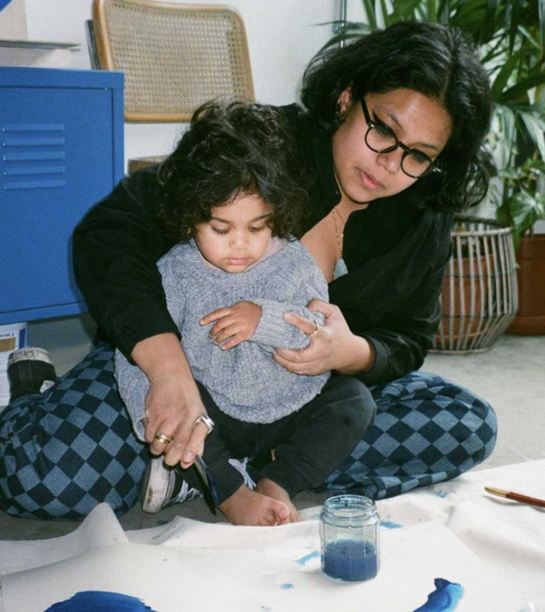 Artist Laxmi Hussain and her child creating artwork on the floor of her studio