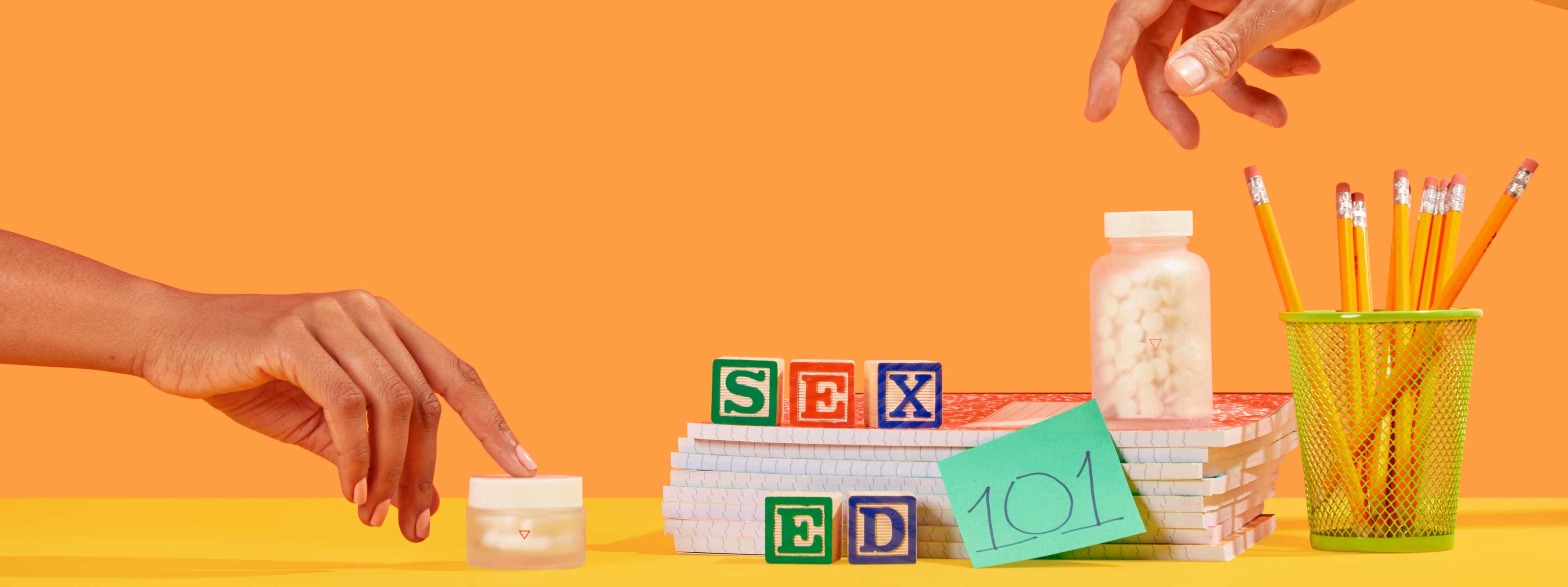 Desktop scene with Wisp medication, pencils and Sex Ed 101 spelled out with building blocks