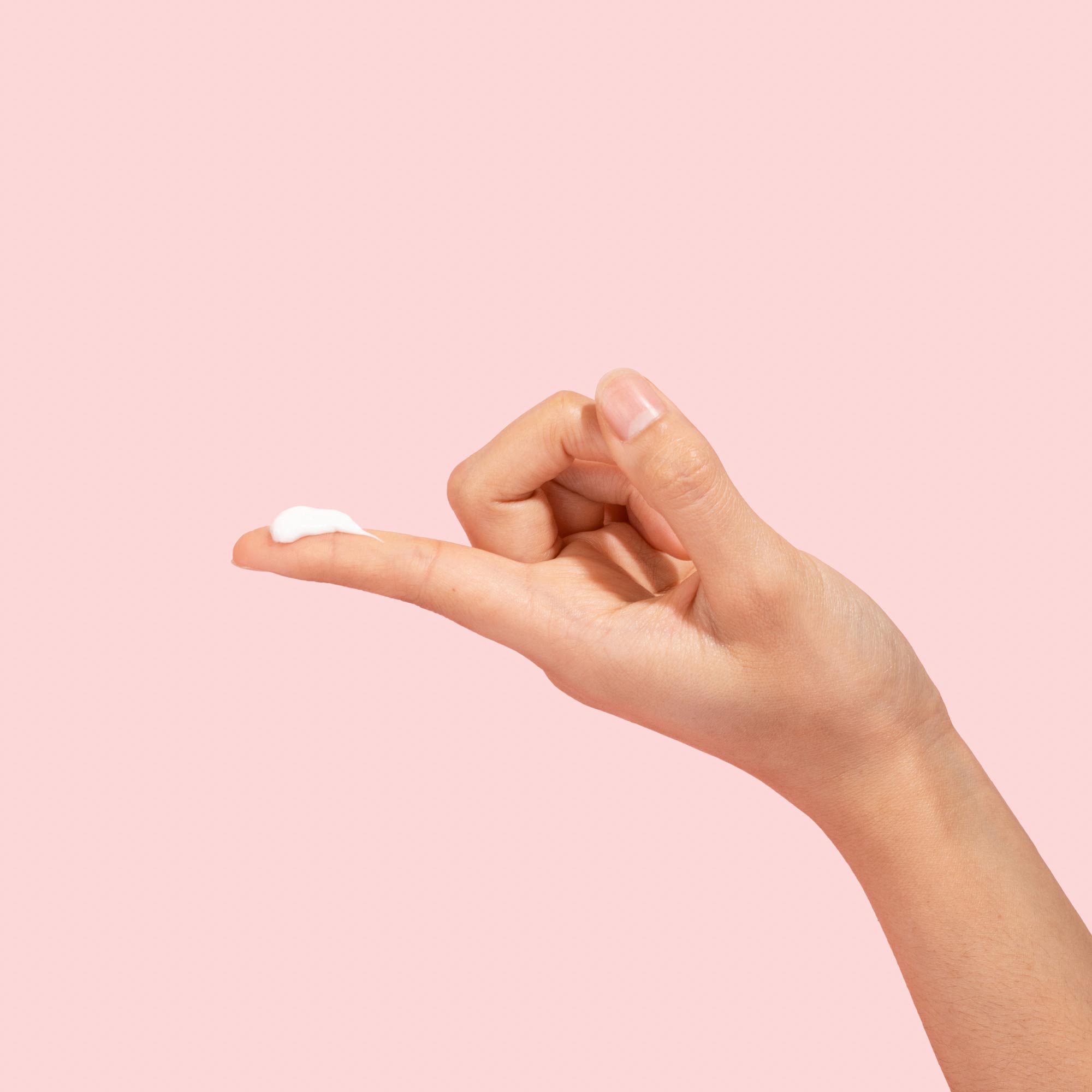 Hand with smear of topical lidocaine cream on finger on pink background