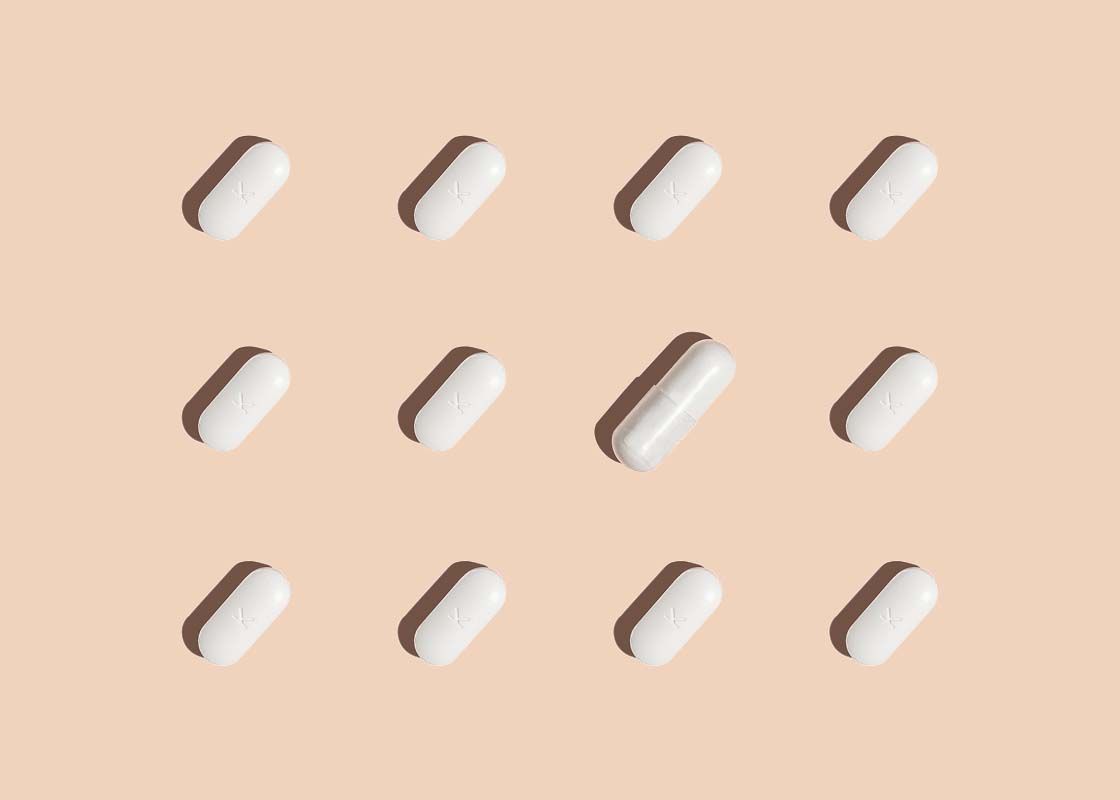 12 white pills laid out in rows on a cream surface