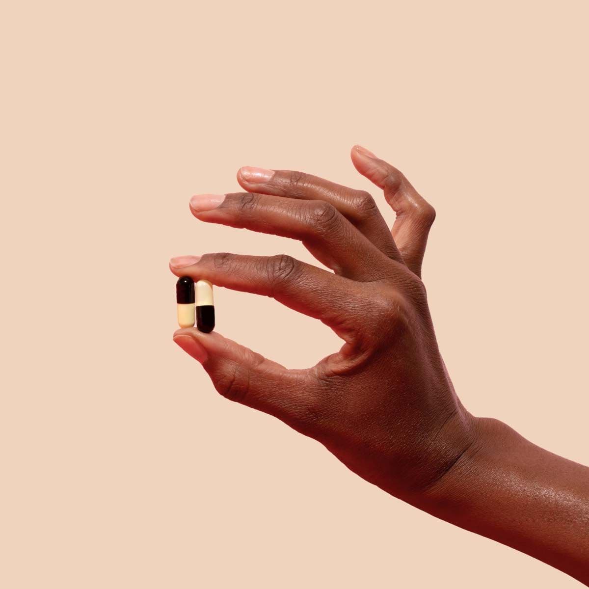 Woman's hand holding UTI antibiotics on a cream background