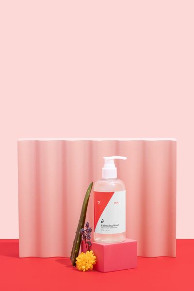 Wisp Balancing Wash with Aloe Vera, Lavender, Marigold and colorful abstract shapes on a pink and red background