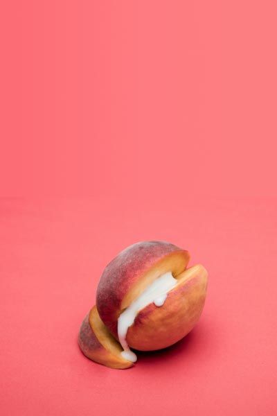 A cut open apricot with a cream substance in the middle on a red background