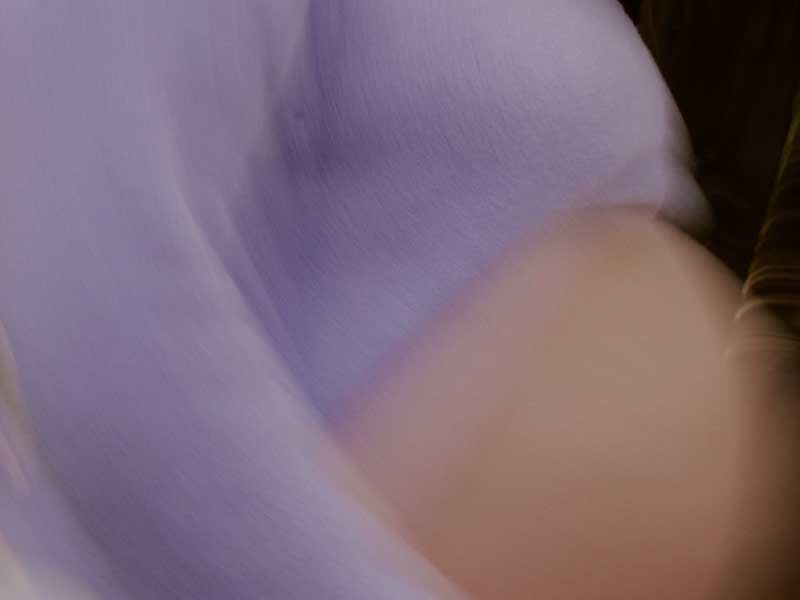 Soft, blurred close-up of a pregnant torso in motion.