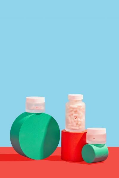 3 Wisp glass pill jars balanced on colorful abstract shapes with a light blue and red background