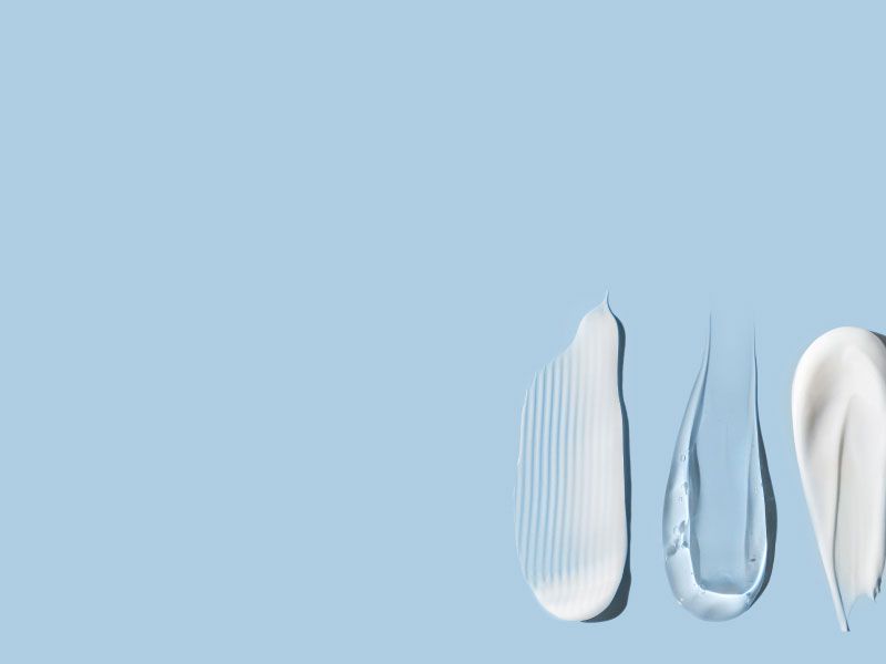 Skincare cream and gel swatches on a light blue surface