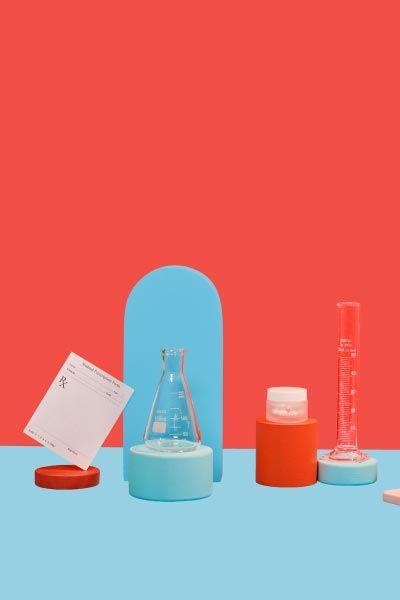 A small Wisp glass jar, test tubes, and rx script and a person's hand reaching for a mobile phone with colorful abstract shapes