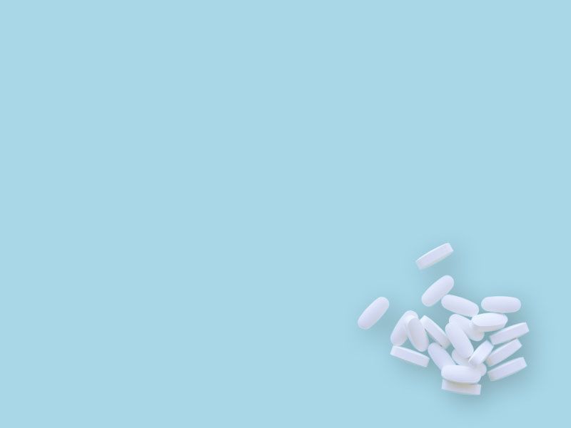 A small pile of white pills on a light blue surface