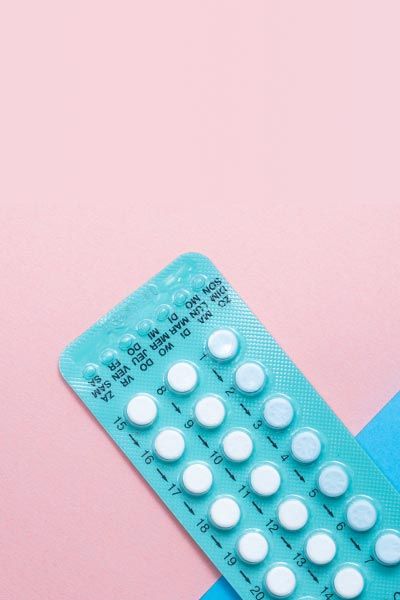 A blue birth control packet on a pink and light blue background