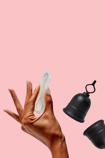 A woman's hand holding the Flex Disc next two two Flex Menstrual Cups with a pink background
