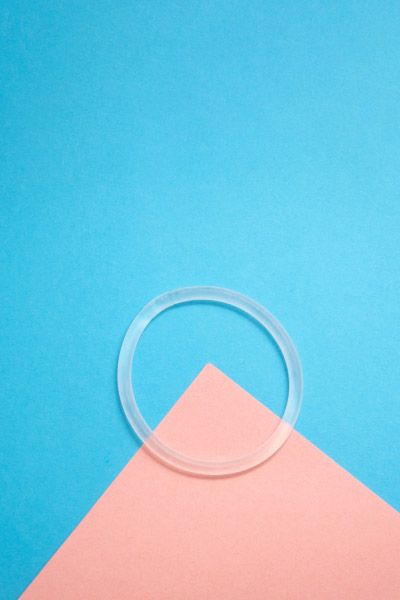 Nuvaring the vaginal birth control ring sitting on a pink and blue geometric background