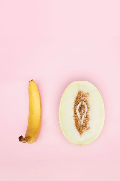 A suggestive cut open fruit and a banana on a pink background