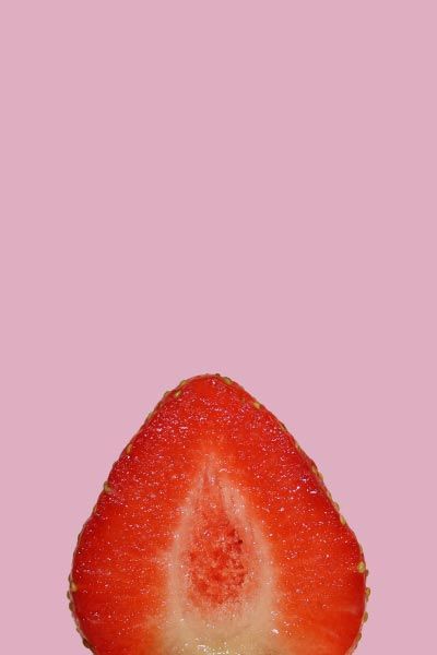 A cut open vulva shaped strawberry with a purple background