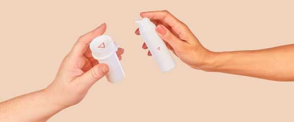 Two people's hands holding a Wisp pill vial and a Wisp pump bottle with a cream background