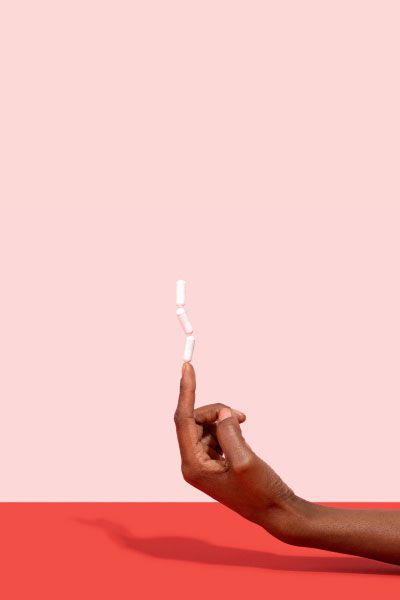 Hand balancing 3 pills on their pointer finger with a pink and red background