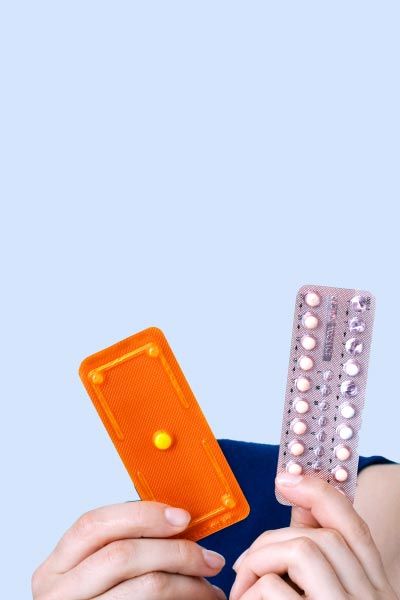 Woman holding an Emergency Packet and a Birth Control packet or a gray blue background