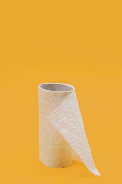 An almost empty toilet roll sitting on a yellow surface