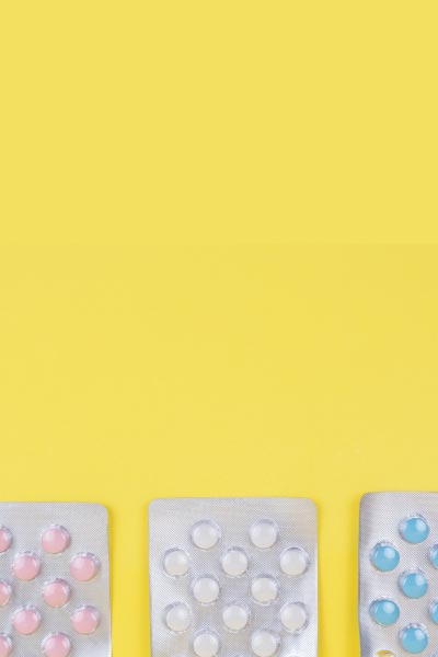 3 packets of colorful pills on a yellow background