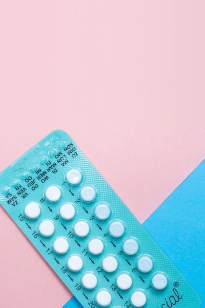 A blue birth control packet on a pink and light blue surface