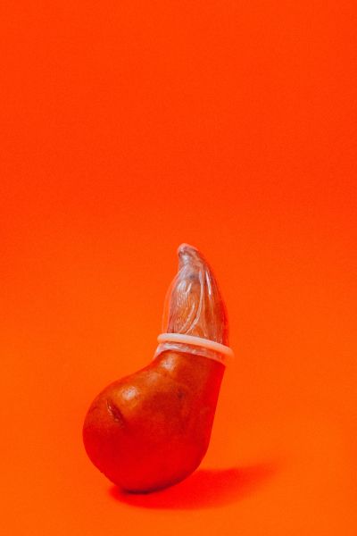 a red fruit wearing a condom on an orange background