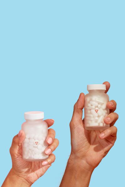 Two hands holding Wisp Valacyclovir and Acyclovir glass jars with a light blue background