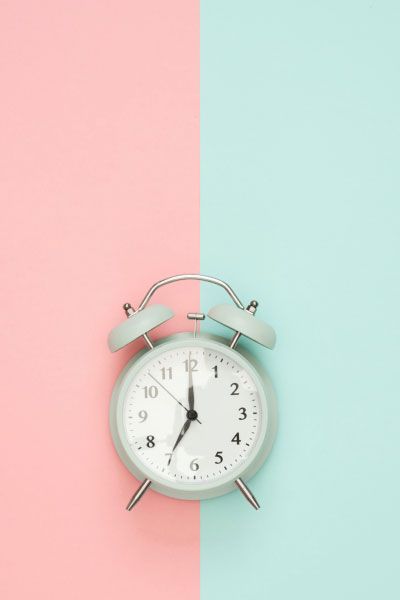 Mint colored alarm clock on a peach and mint colored background